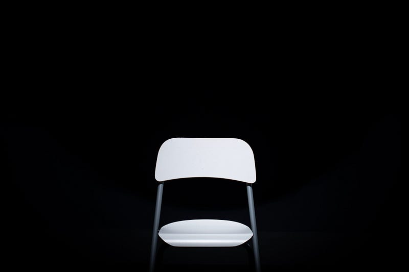 a white chair with no one in it, against a black background