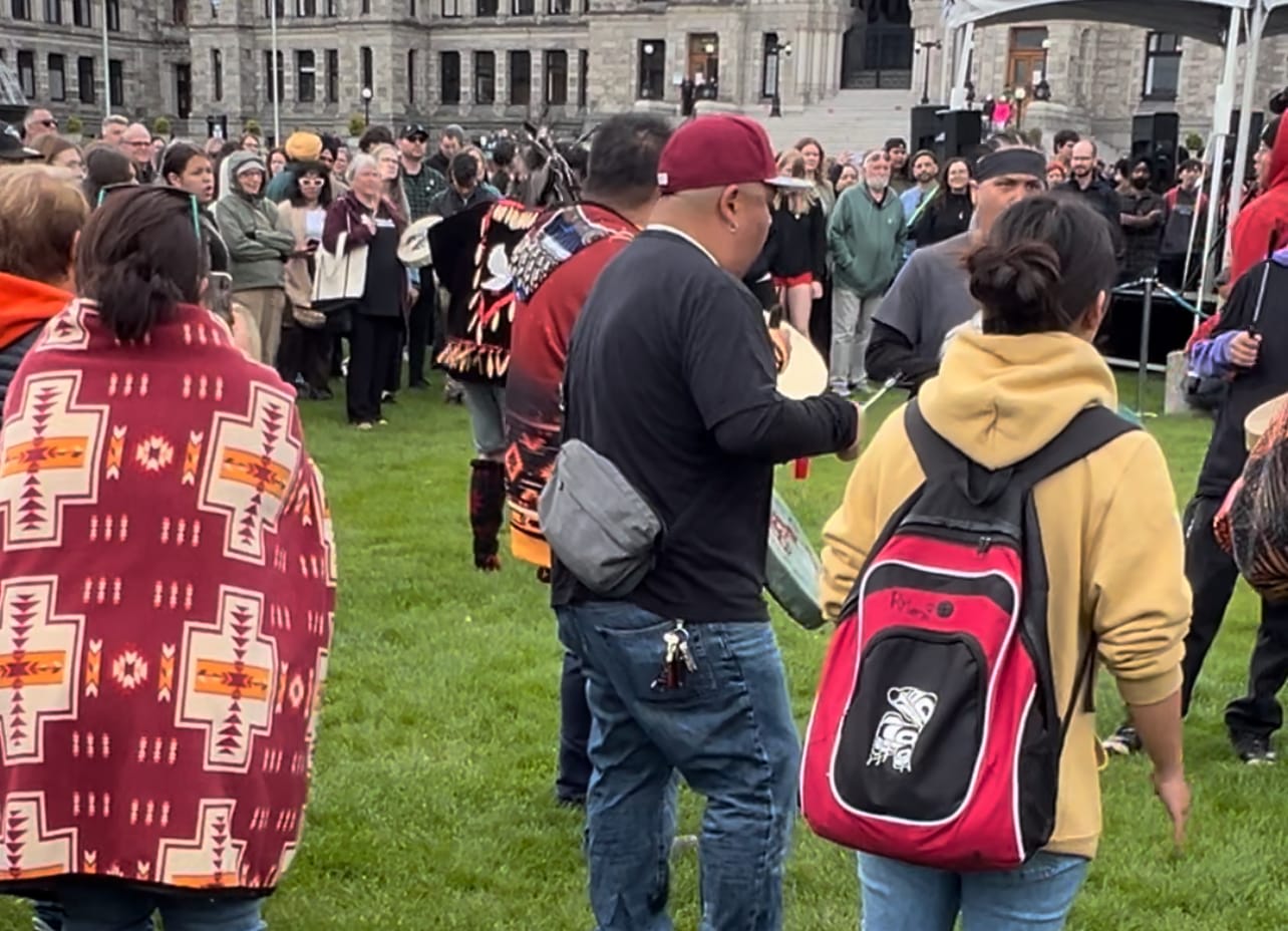 an indigenous drum circle and indigenous dancers are surrounded by a crowd