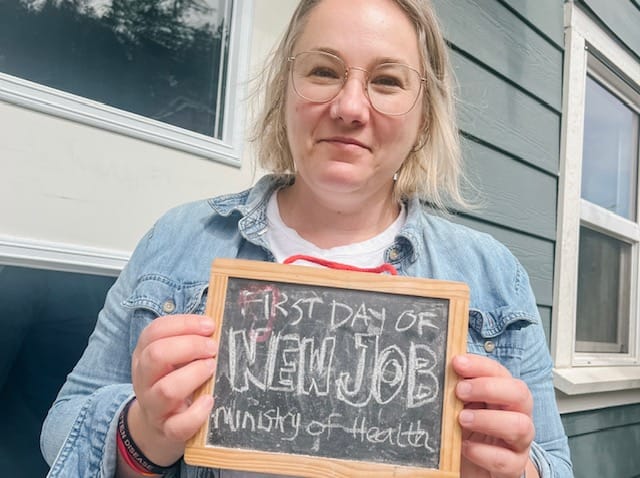 woman (me) holding a sign that says "first day of new job, ministry of health"