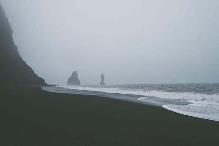 A beach, waves and a grey, foggy sky