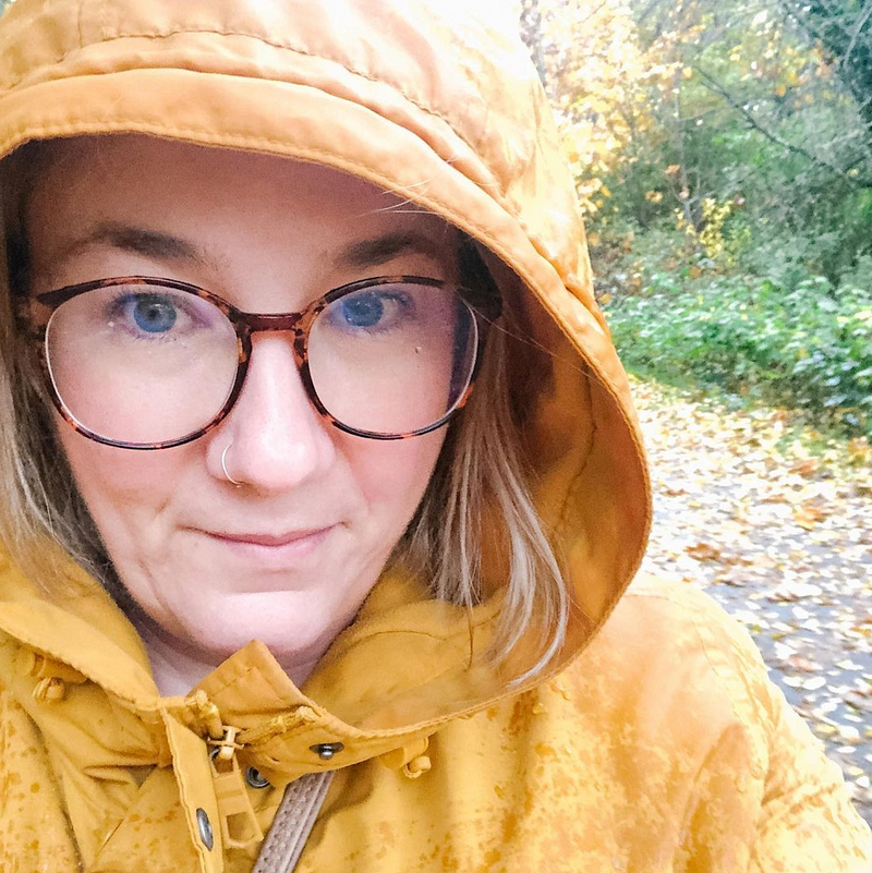 women in glasses wearing yellow coat outside in the rain